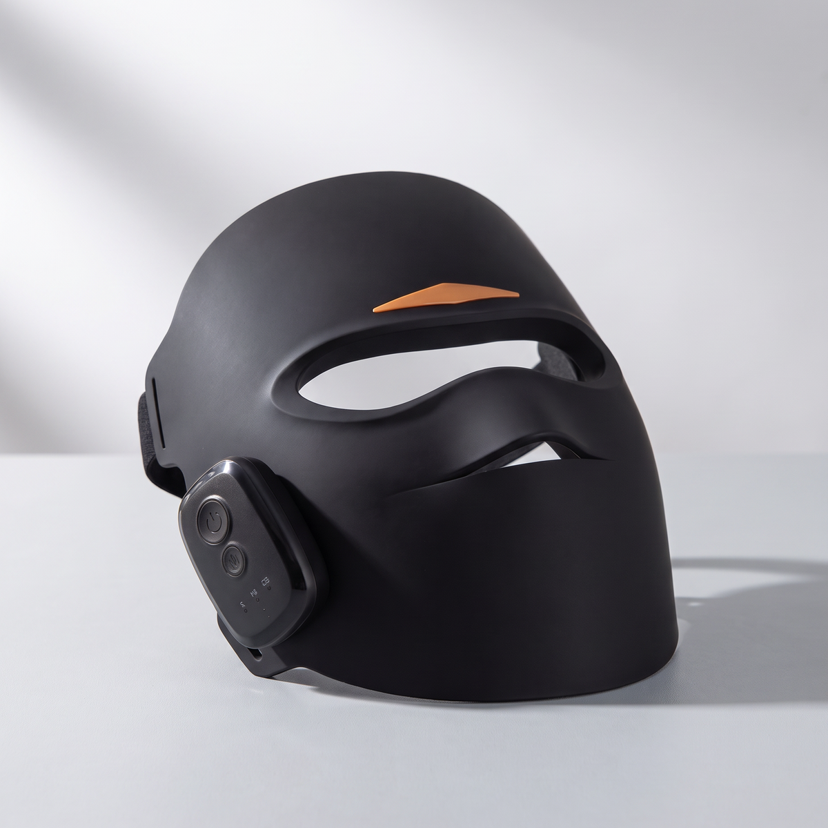 Aura Pro LED light therapy mask in black with magnetic controller and adjustable head strap, studio shot on a light grey background